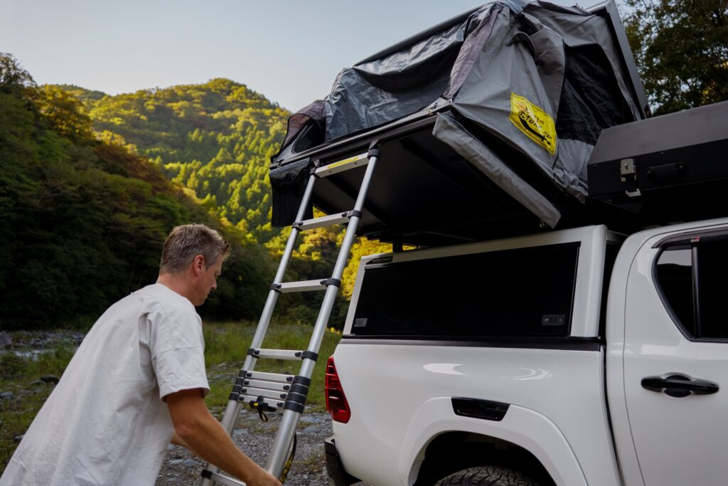Setting the ladder against a rooftop tent on a Hilux camper