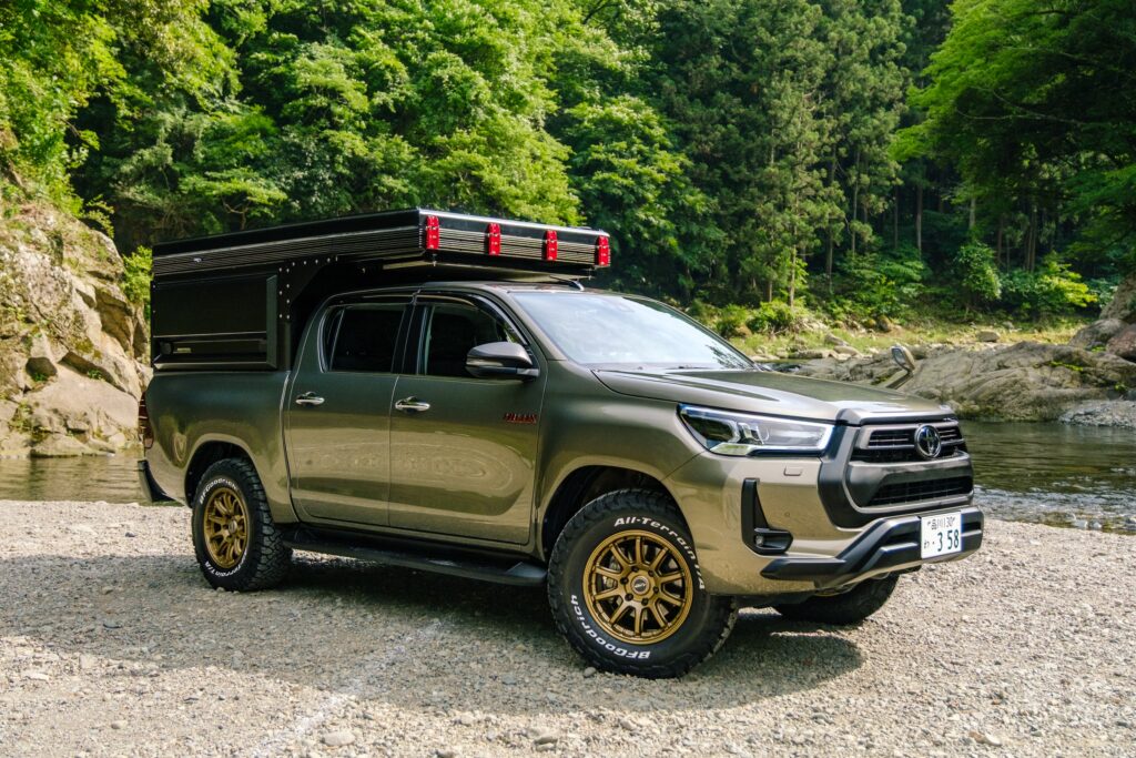 The Hilux Cabin, an enclosed camper body on a Toyota Hilux, parked beside a river