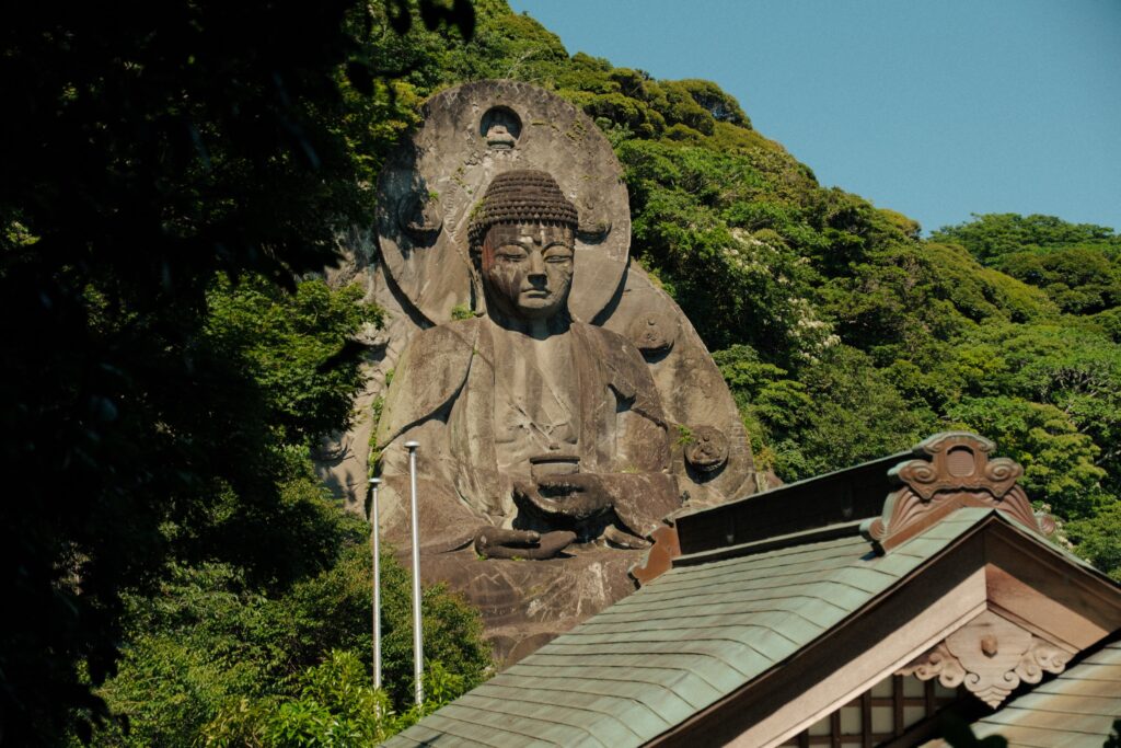 千葉の田舎で、寺の屋根の上の森に覆われた崖に彫られた大仏