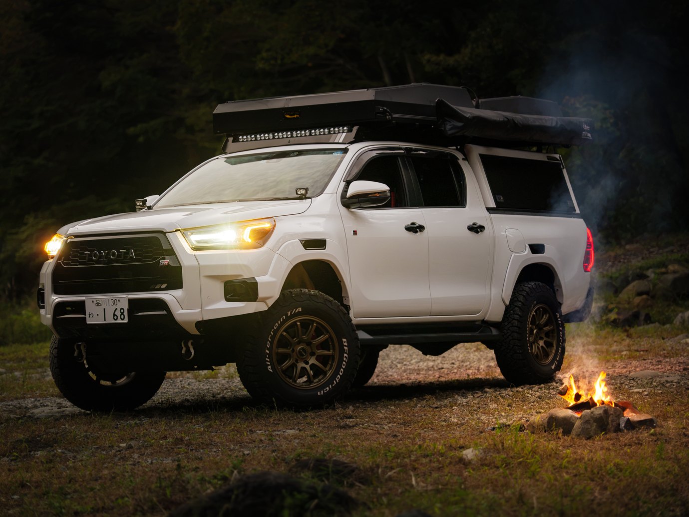 ヘッドライトを灯した夜のHiluxと、横の小さな焚き火
